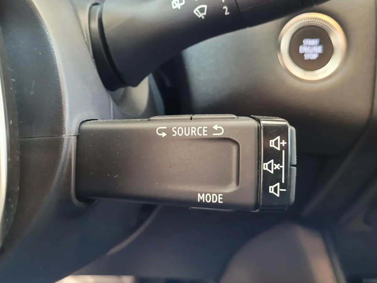 Gros plan sur la commande au volant du Renault Captur Business gris clair, avec bouton démarrage visible en arrière-plan.