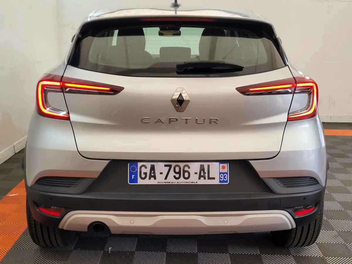 Vue arrière d'un Renault Captur Business Blue dCi 95 gris clair avec feux LED allumés dans un garage.