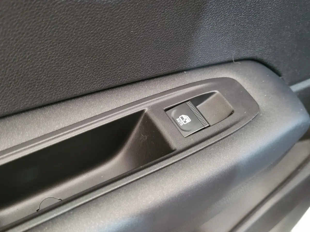 Gros plan sur le bouton de commande de la vitre électrique côté conducteur d'une Renault Captur gris clair 2021.