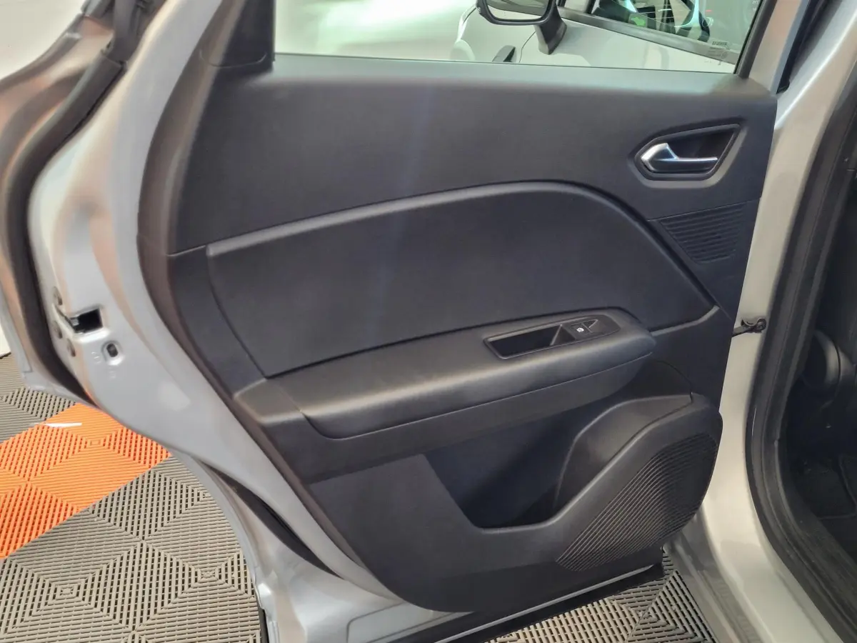 Porte arrière droite ouverte d'un Renault Captur gris clair, montrant le panneau intérieur noir avec commande de vitre.