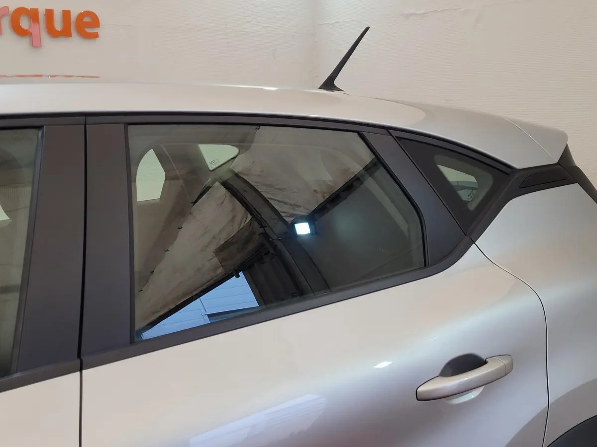 Vue latérale côté droit du Renault Captur Business gris clair, mettant en valeur la porte arrière et la lunette teintée.