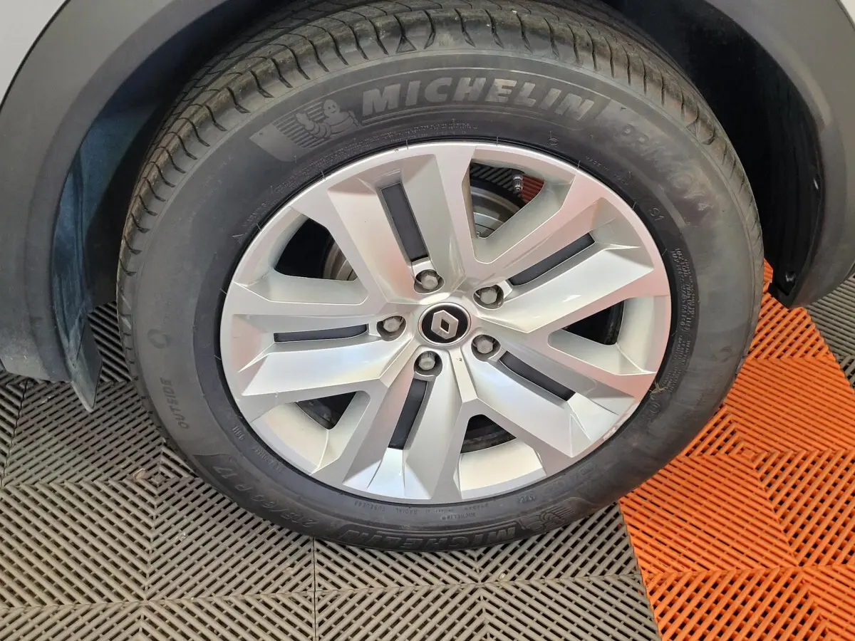 Gros plan sur la roue avant droite d'un Renault Captur gris clair, jante alliage et pneu Michelin visible.