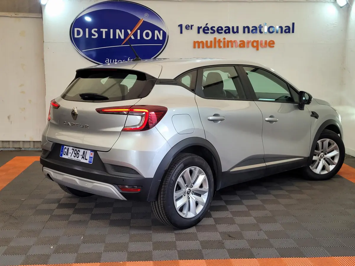 Vue 3/4 arrière droite d'un Renault Captur gris clair 2021 avec feux LED et jantes alliage en showroom.
