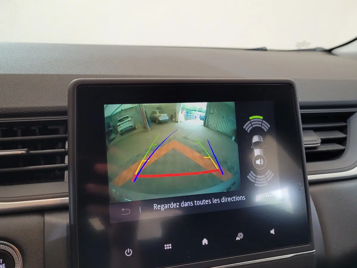 Écran tactile intérieur montrant la caméra de recul et l'aide au stationnement du Renault Captur gris clair 2021.