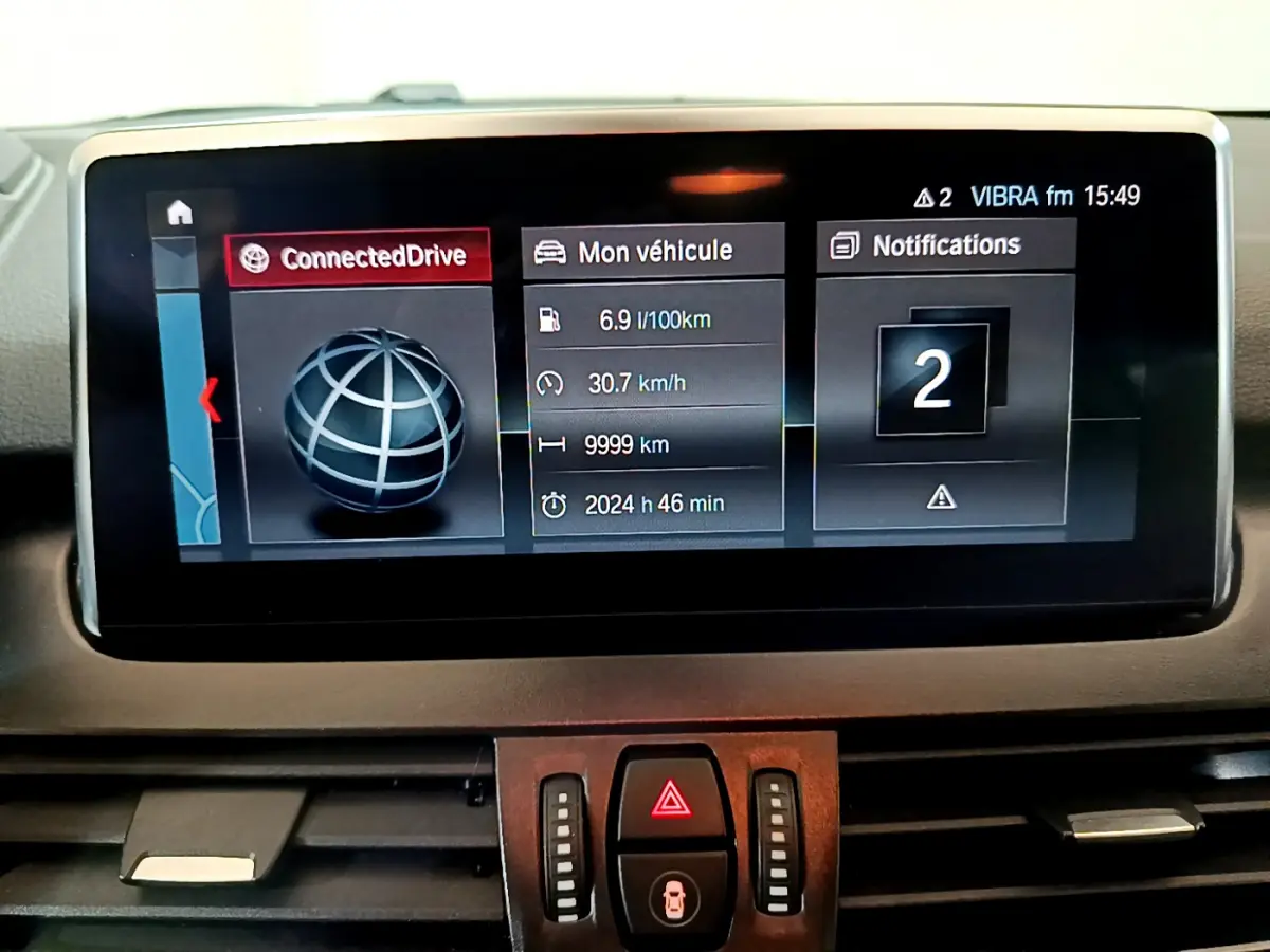 Écran central du tableau de bord de BMW Série 2 Gran Tourer 218d gris clair, affichage connecté et informations véhicule.