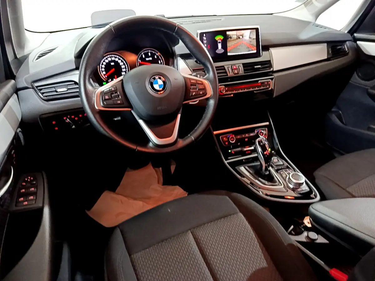 Intérieur BMW Série 2 Gran Tourer 218d Lounge 2020, vue du poste de conduite avec volant cuir, écran central et levier de boîte auto.