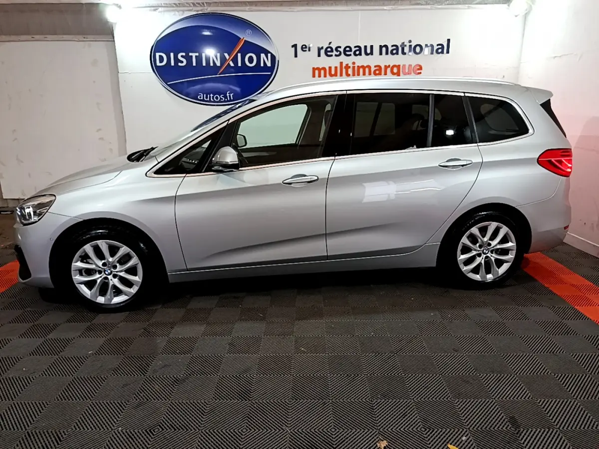 Vue de profil côté gauche d'une BMW Série 2 Gran Tourer 218d Lounge gris clair dans un showroom intérieur.