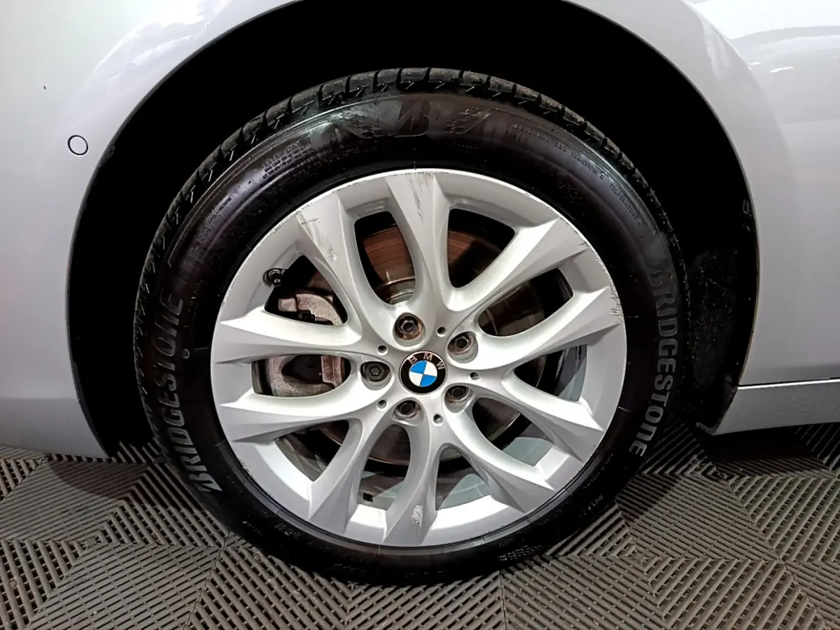 Gros plan sur la roue avant droite grise d'une BMW Série 2 Gran Tourer F46 avec jante alliage à 10 branches.