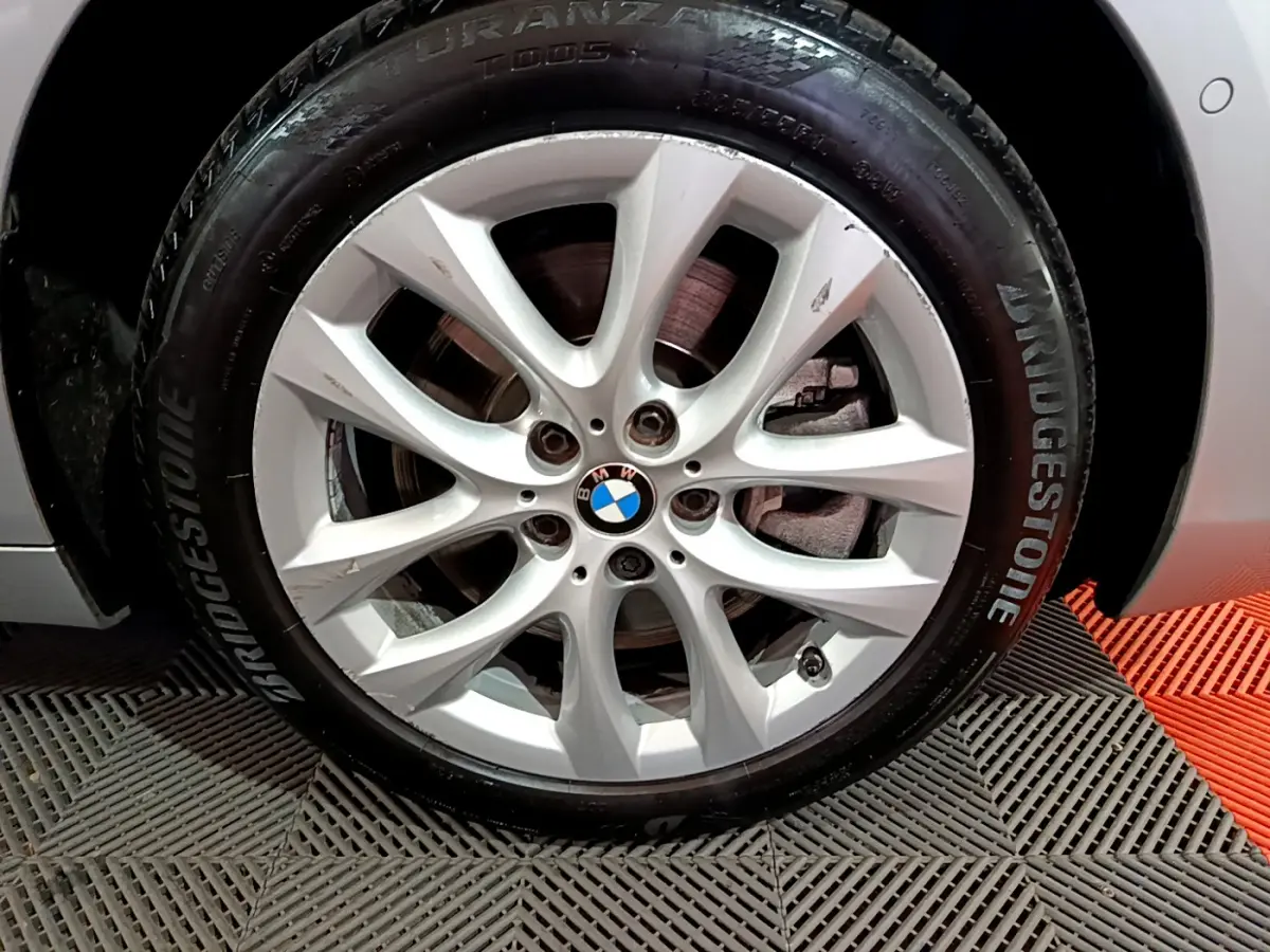 Gros plan sur la roue avant droite d'une BMW Série 2 Gran Tourer gris clair avec jante alliage et pneu Bridgestone.