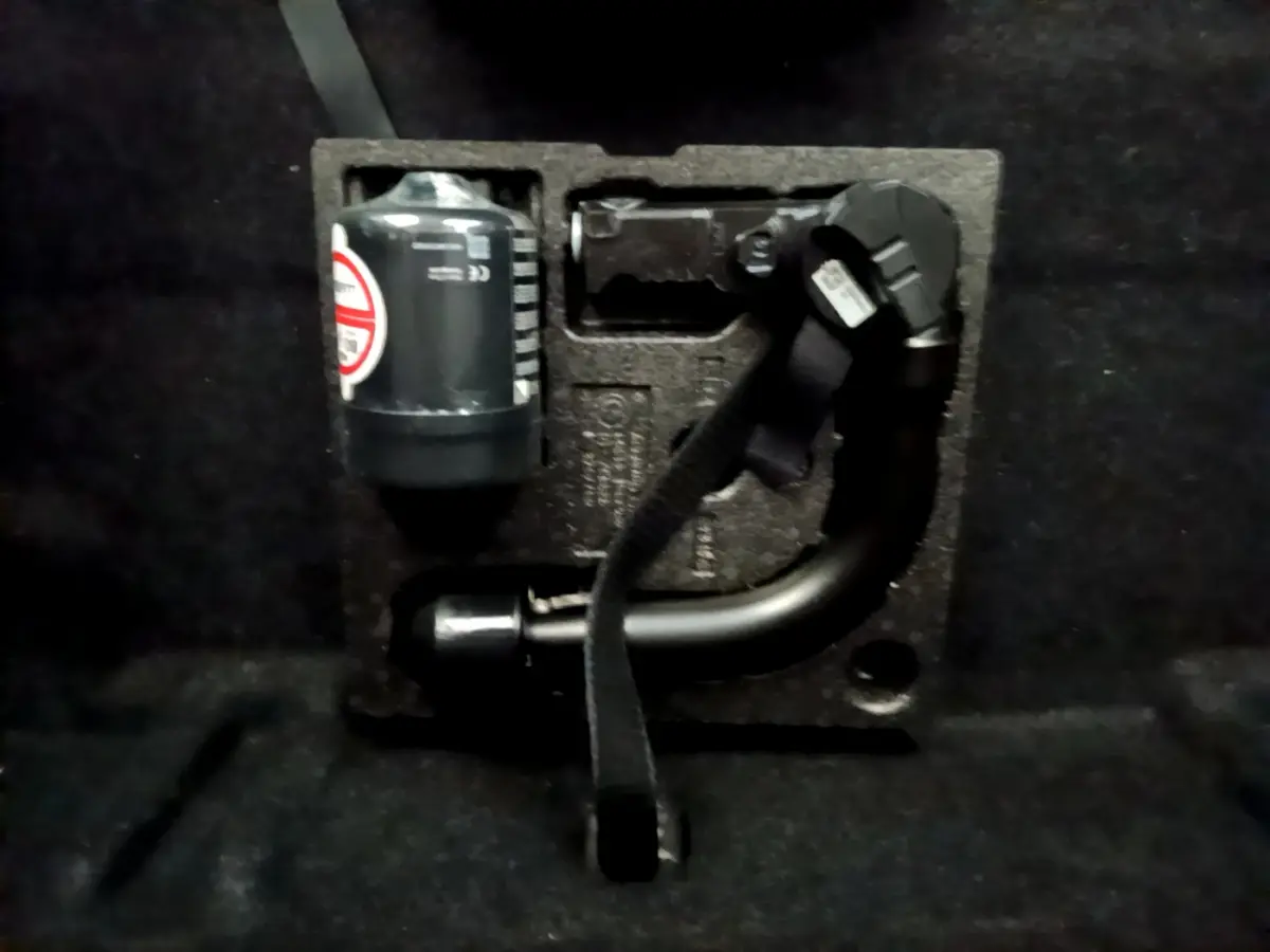 Gros plan sur le coffre d’une BMW Série 2 Gran Tourer gris clair, montrant le kit de réparation pneu intégré.