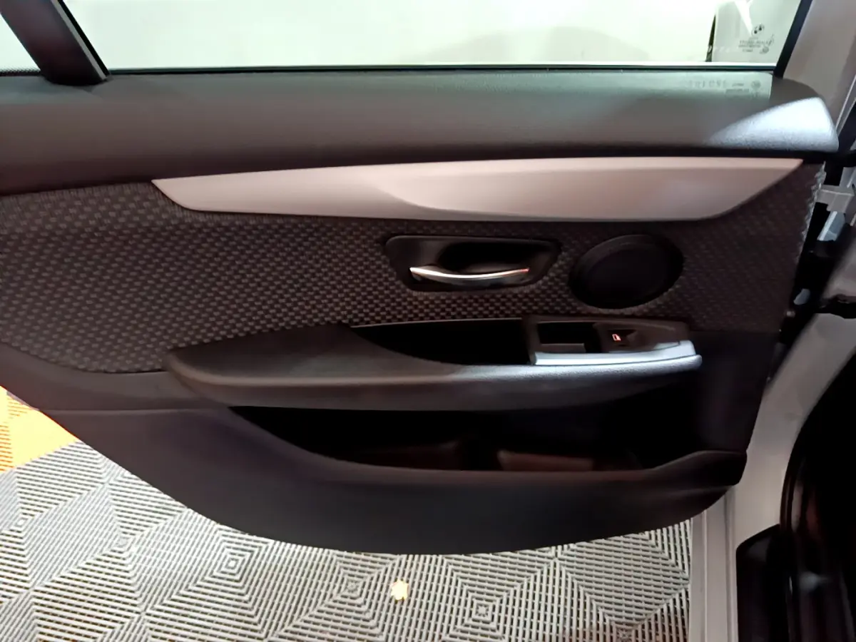Vue rapprochée de la porte avant droite gris clair de la BMW Série 2 Gran Tourer avec garniture noire et poignée chromée.