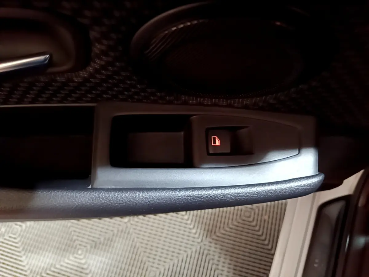 Gros plan sur le bouton de verrouillage de porte intérieur côté conducteur d'une BMW Série 2 Gran Tourer gris clair.