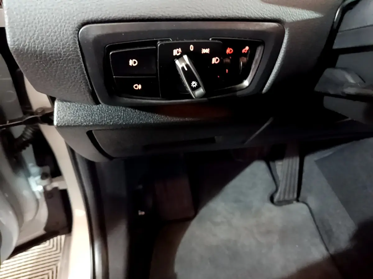 Vue intérieure côté gauche du tableau de bord d'une BMW Série 2 Gran Tourer 218d gris clair, avec commandes d'éclairage.