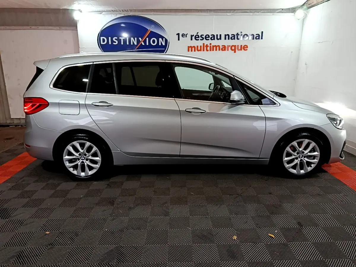 Profil côté gauche d'une BMW Série 2 Gran Tourer 218d Lounge gris clair, avec toit surélevé et vitres teintées.