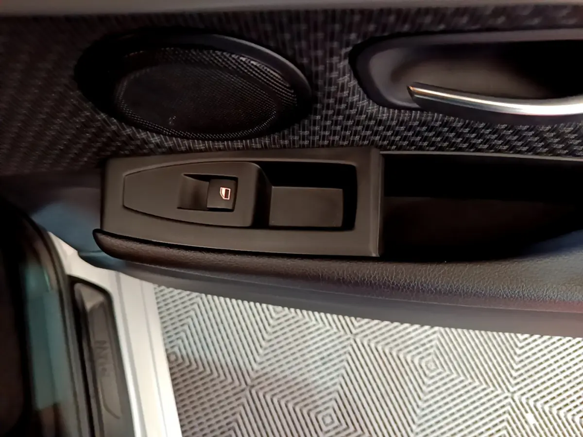 Détail de la commande de lève-vitre sur la porte côté conducteur d’une BMW Série 2 Gran Tourer gris clair.