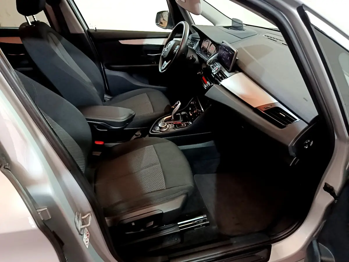 Intérieur avant droit de la BMW Série 2 Gran Tourer 218d gris clair, sièges tissu noirs et tableau de bord moderne.