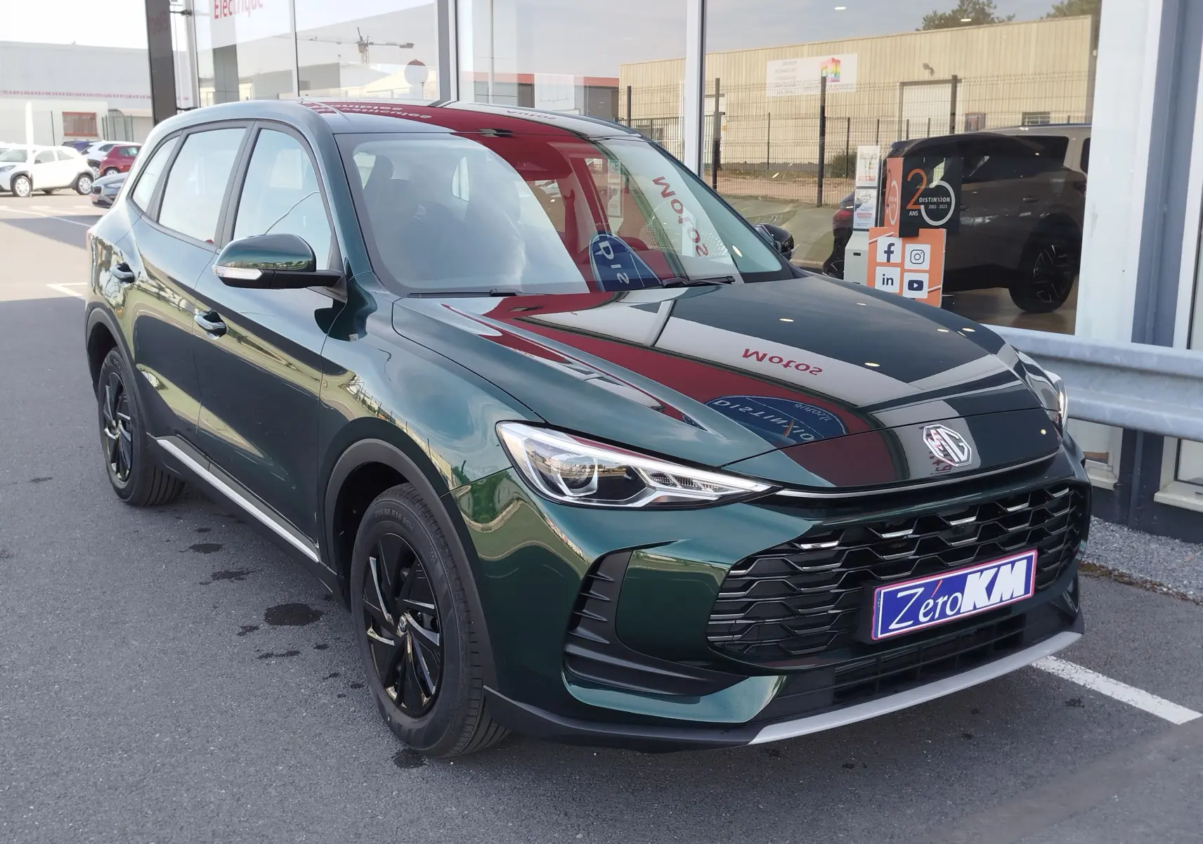 MG ZS 2026 vert émeraude en 3/4 avant droit, avec calandre noire et jantes alliage noires, stationné devant un showroom.