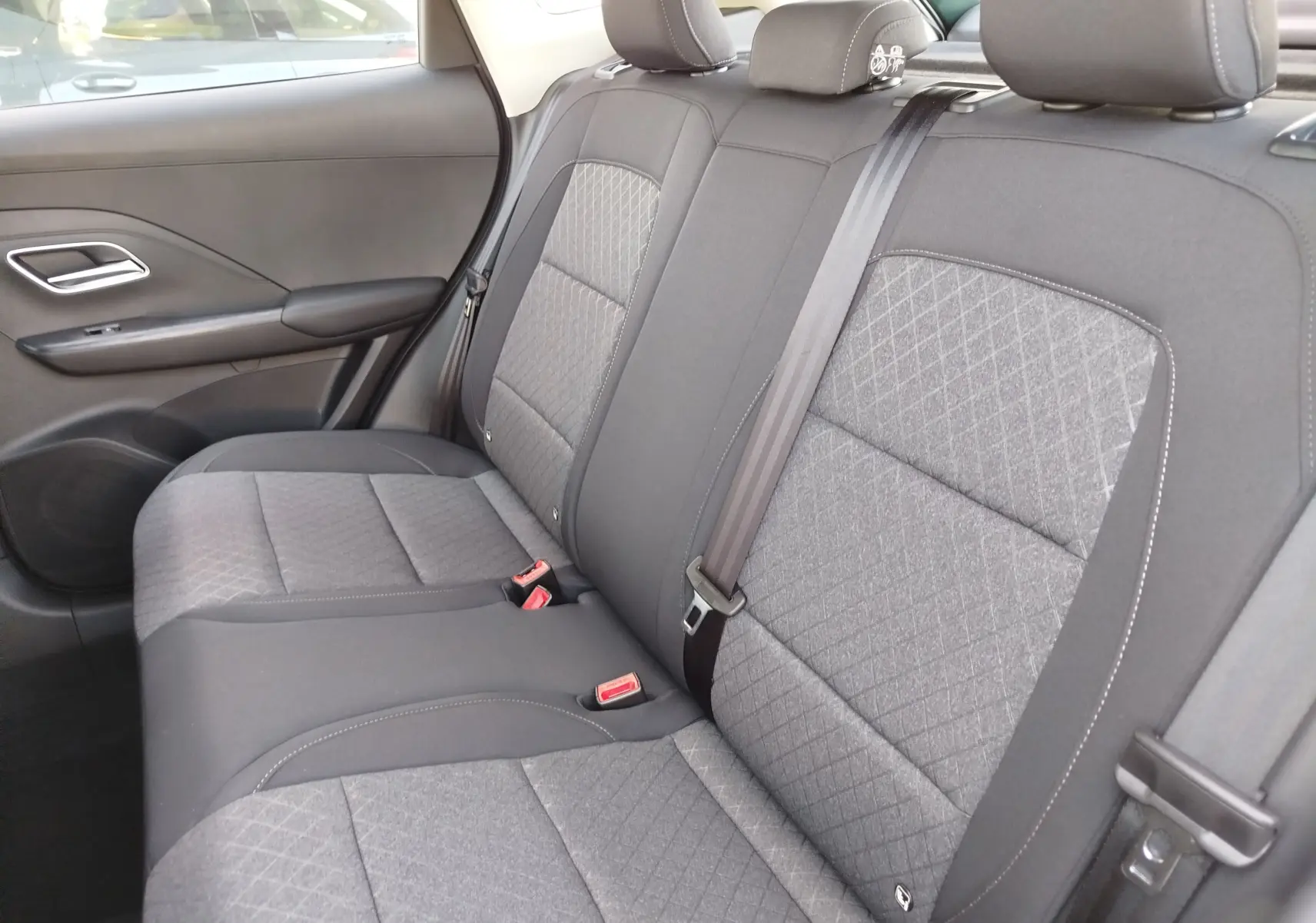 Vue intérieure côté droit des sièges arrière gris tissu du MG Motor ZS 1.5L Hybrid+ 2026 avec ceinture de sécurité noire.
