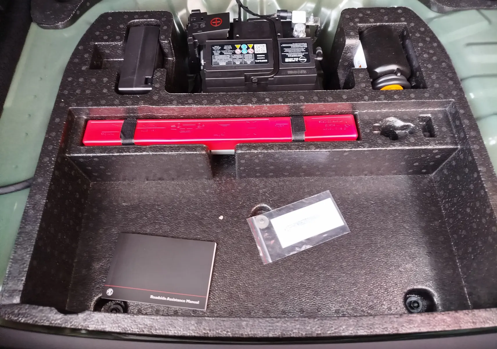 Vue plongeante sur le compartiment de rangement arrière du MG MOTOR ZS 1.5L Hybrid+ 2026, avec batterie et kit de secours.