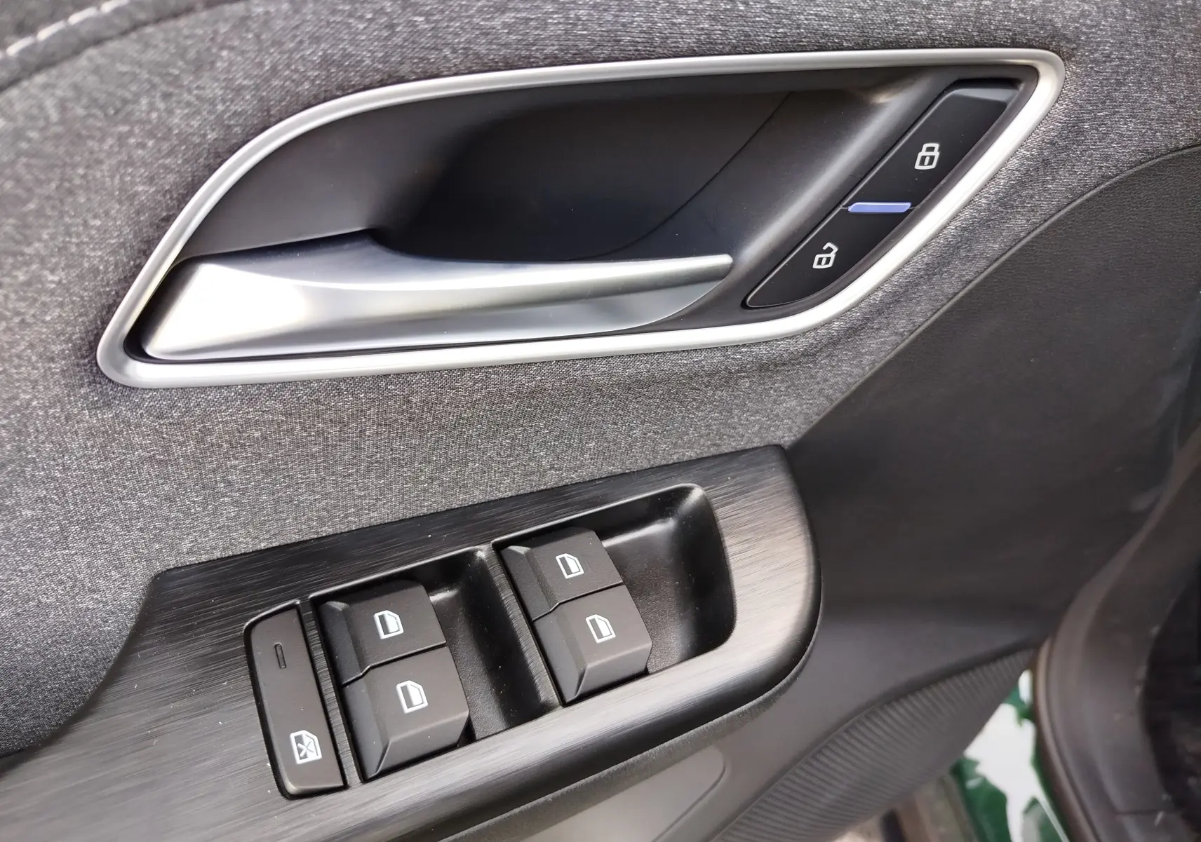Gros plan sur la poignée intérieure et les commandes de vitres côté conducteur du MG ZS Emerald Green 2026.