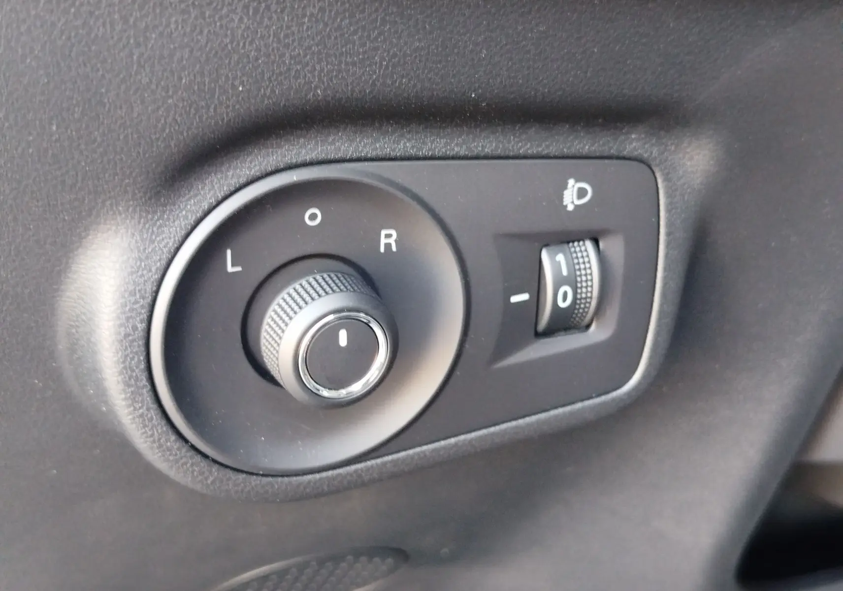 Gros plan sur les commandes noires de réglage des rétroviseurs et de l’éclairage du tableau de bord dans un MG Motor ZS 2026.