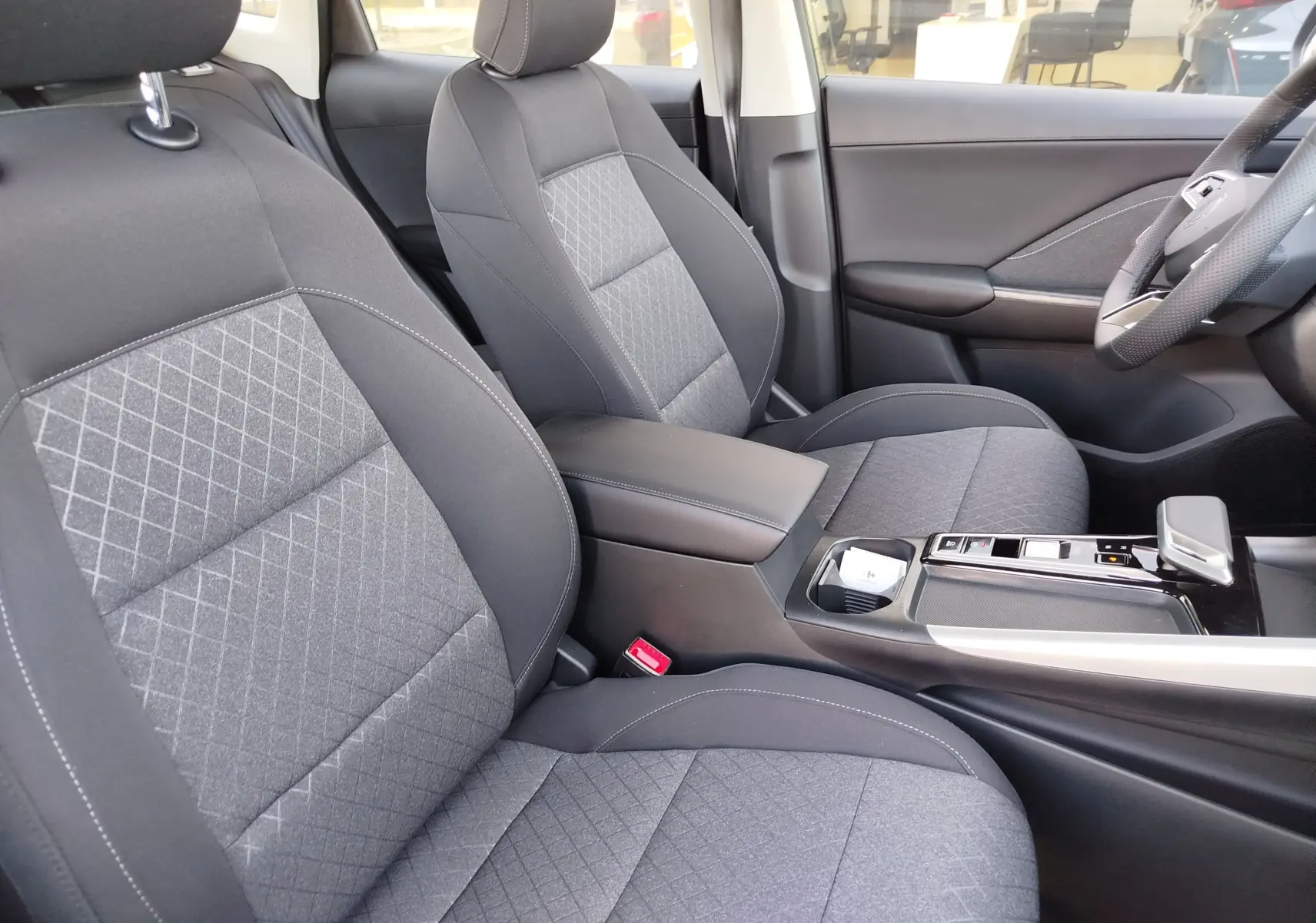 Vue intérieure côté droit du MG ZS 2026, sièges tissu gris avec surpiqûres et console centrale moderne noire.