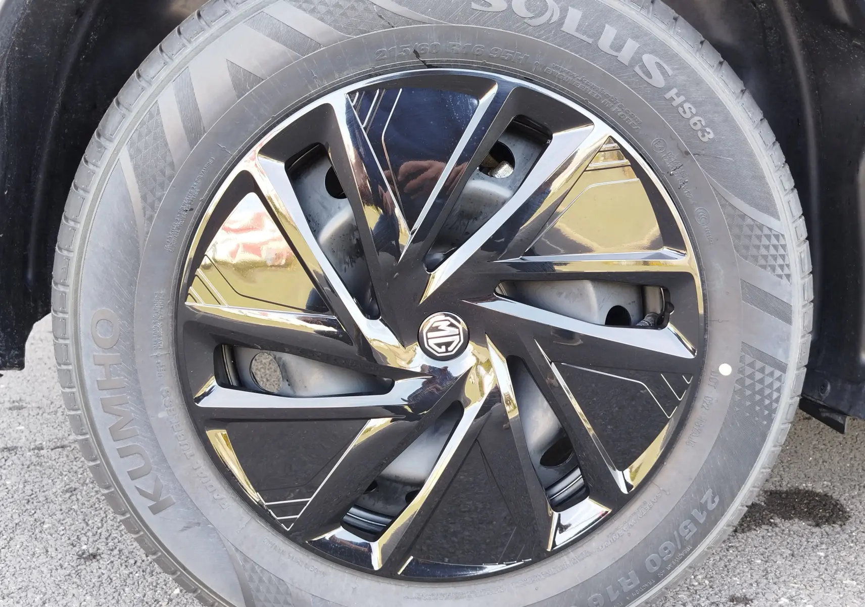 Gros plan sur la jante noire brillante à design géométrique du MG MOTOR ZS 1.5L HYBRID+ 2026, pneu Kumho visible.