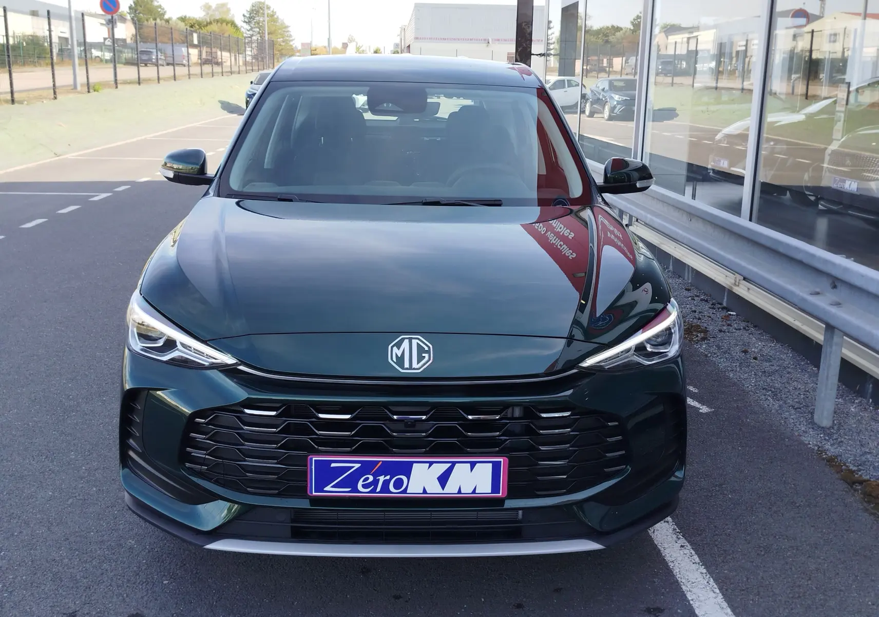 Vue frontale d'un MG ZS 1.5L Hybrid+ 197ch en vert émeraude métallisé, avec calandre noire et phares LED allumés.