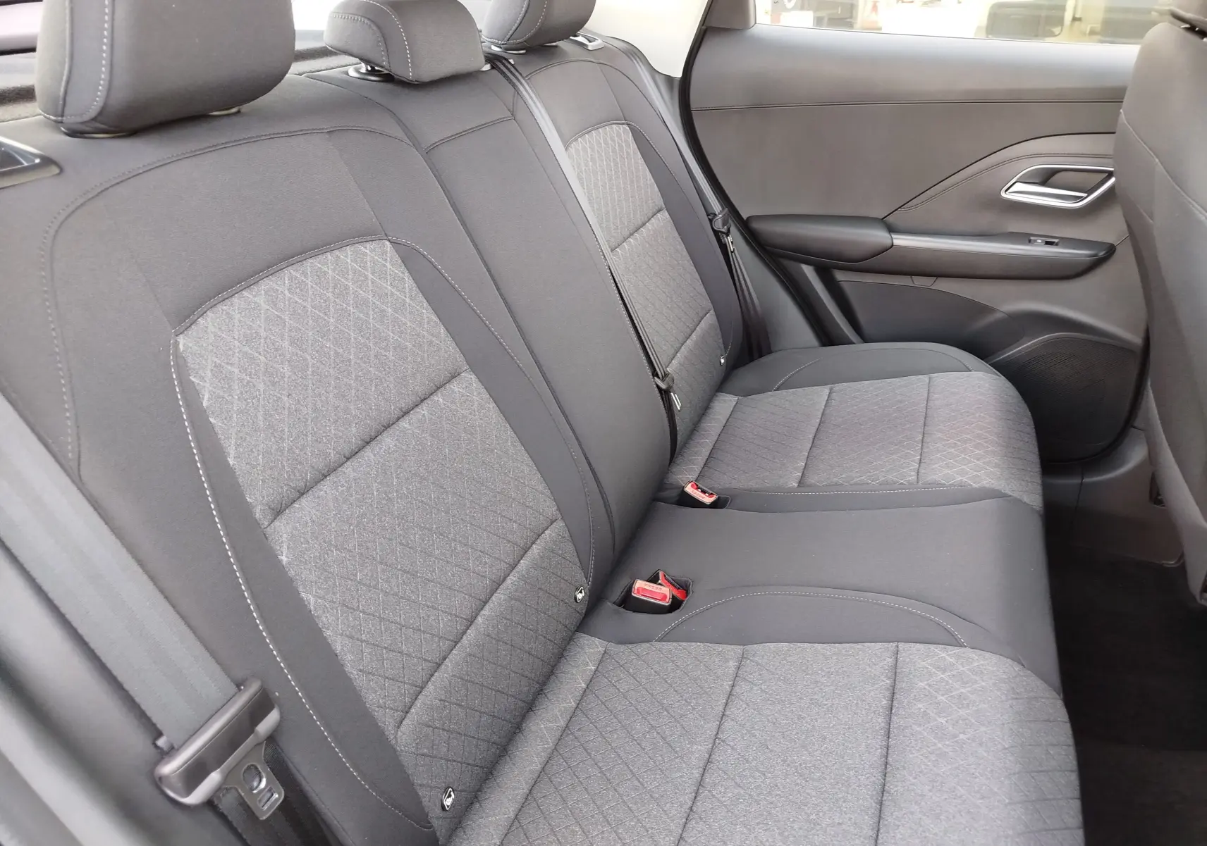 Vue intérieure côté droit des sièges arrière en tissu gris avec motifs géométriques du MG MOTOR ZS 1.5L Hybrid+ 2026.