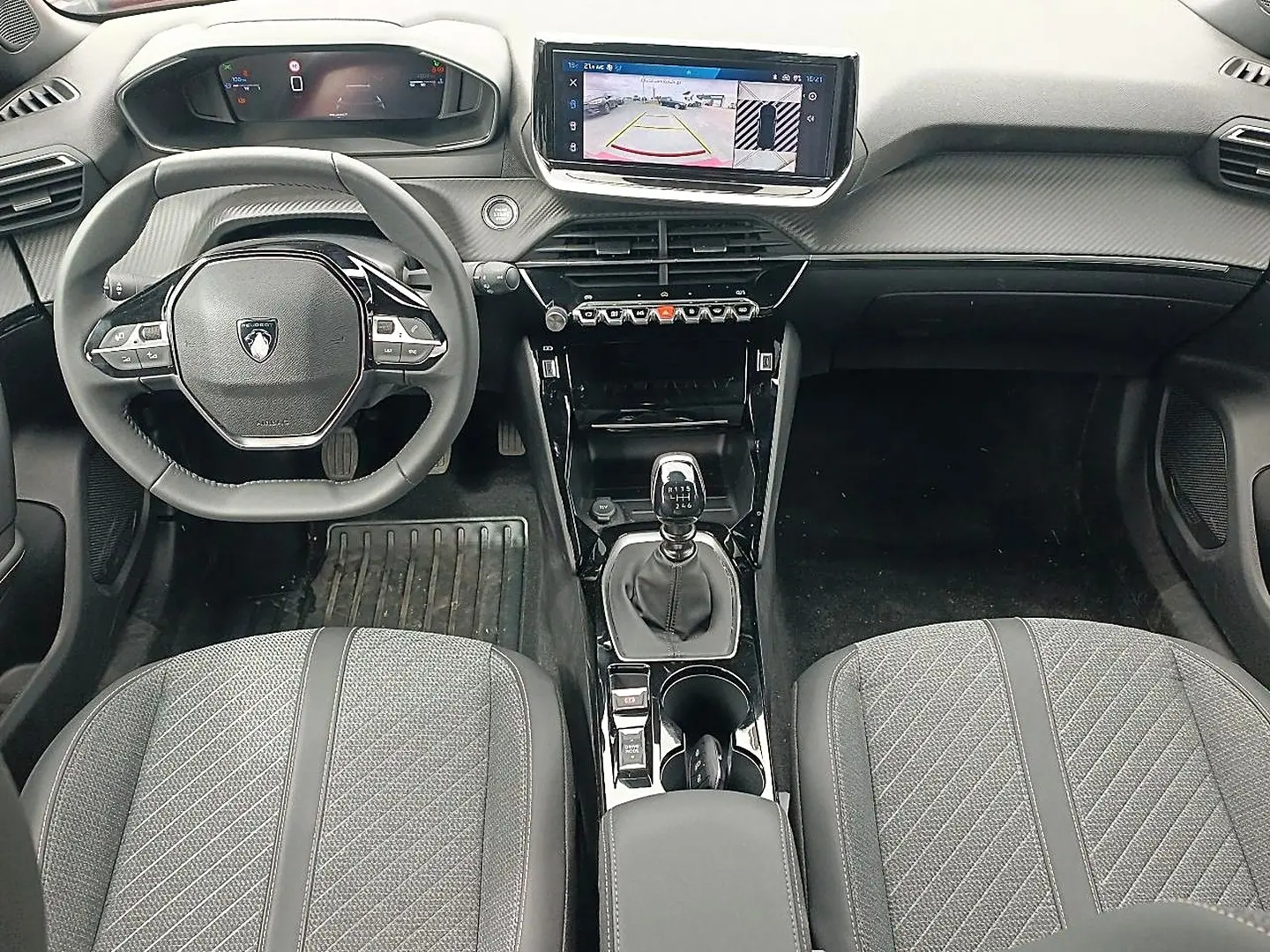Vue intérieure avant du Peugeot 2008 1.2 100 allure 2025, volant multifonction, écran tactile et levier de vitesse manuel.