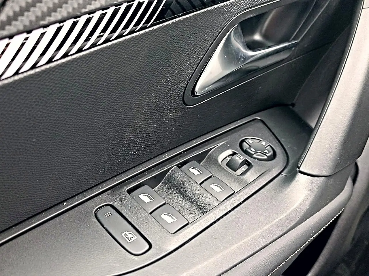 Gros plan sur la commande des vitres électriques côté conducteur de la Peugeot 2008 rouge Elixir, avec poignée intérieure noire.