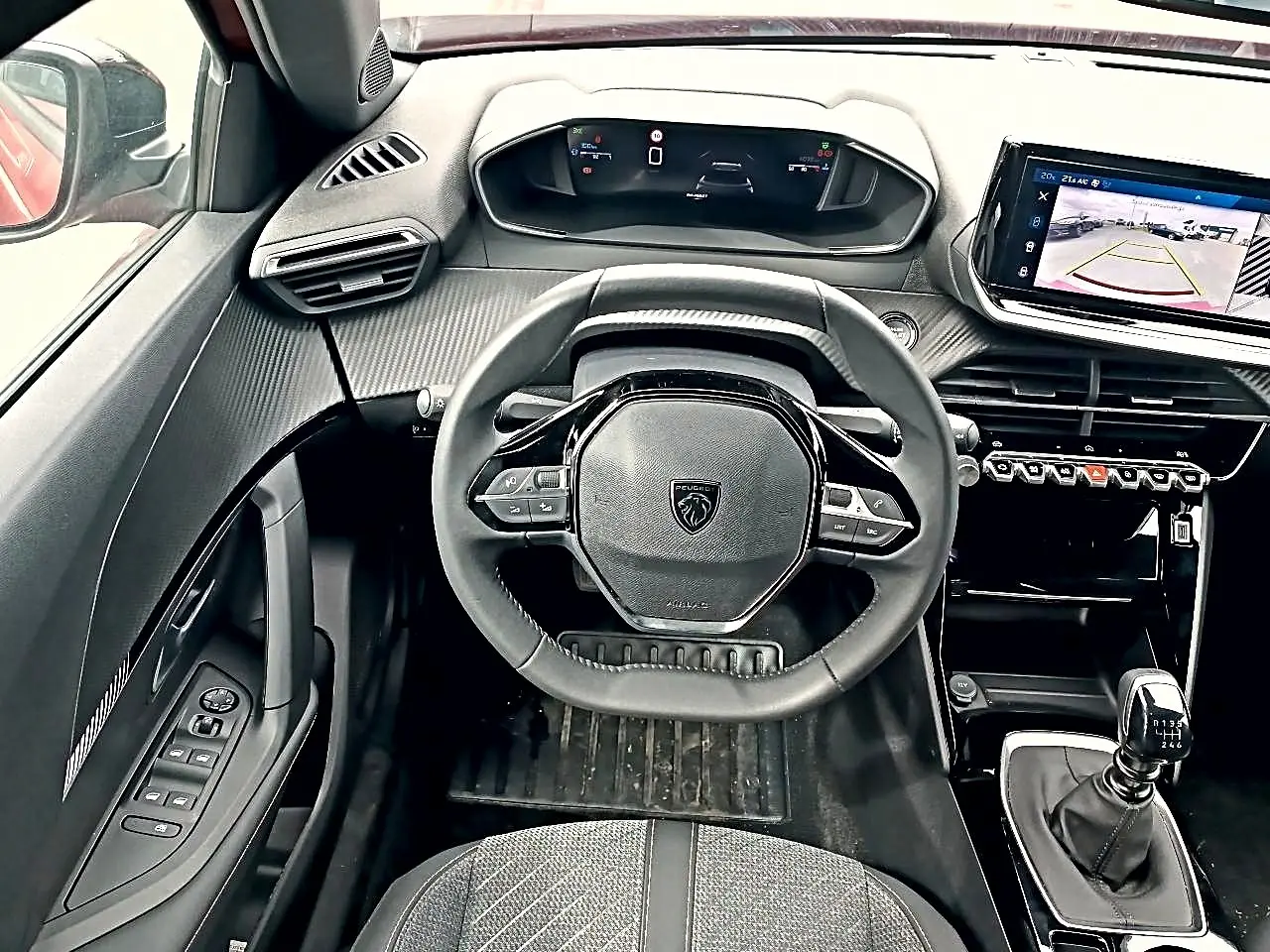 Vue intérieure centrée sur le volant Peugeot 2008 1.2 100 Allure avec tableau de bord digital et levier de vitesse manuel.