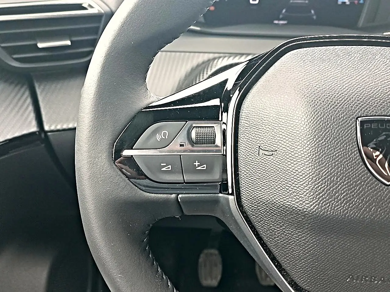 Gros plan sur la partie gauche du volant multifonction noir du Peugeot 2008 avec commandes audio intégrées.