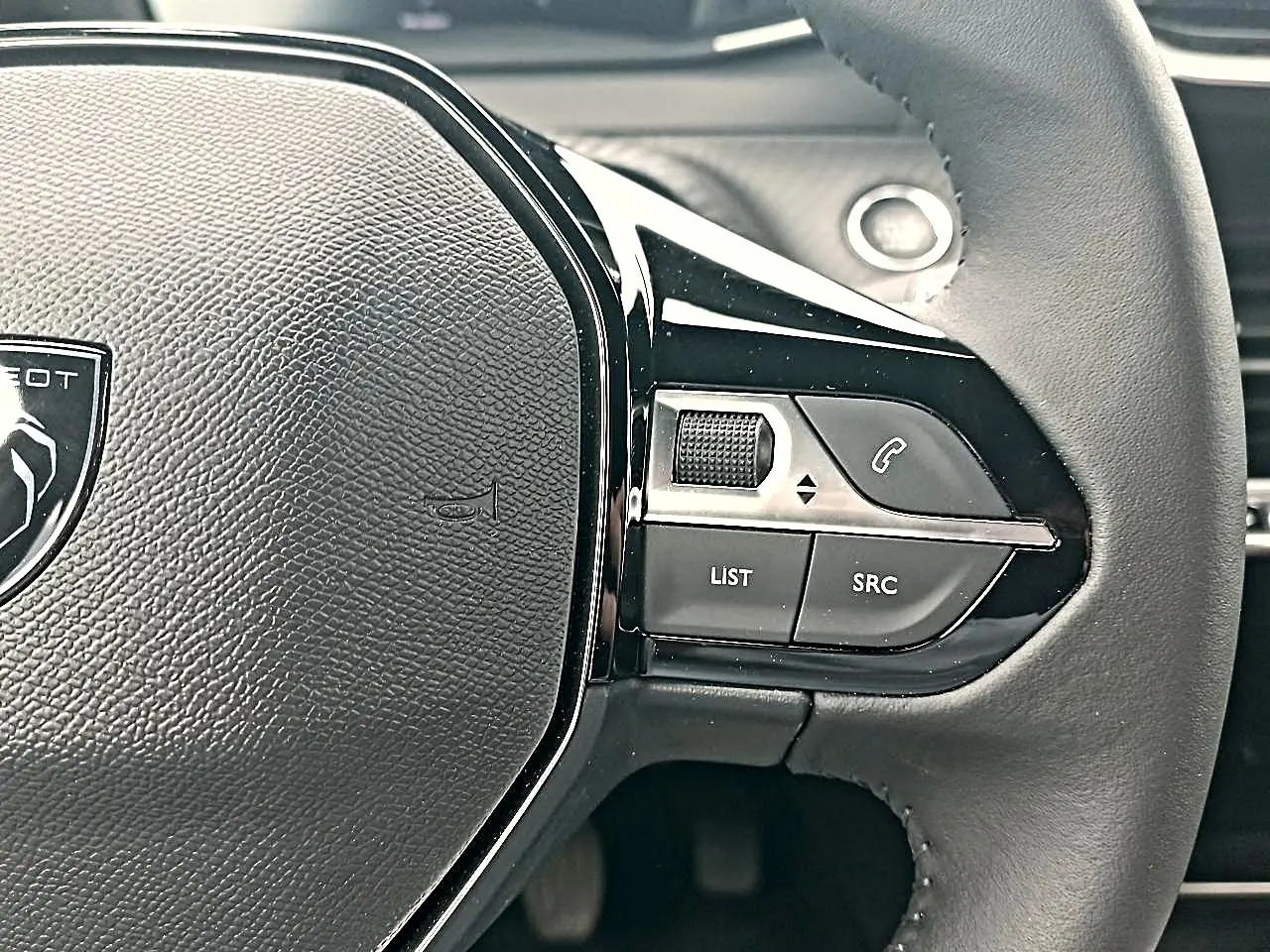 Gros plan sur le volant multifonction noir de la Peugeot 2008 2025 avec commandes audio et téléphone intégrées.