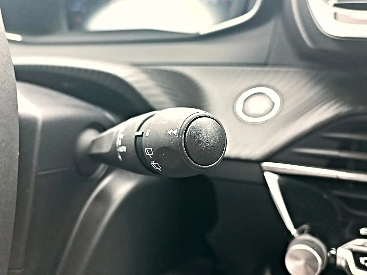 Gros plan sur la commande d’essuie-glace côté gauche du tableau de bord noir du Peugeot 2008 rouge Elixir.