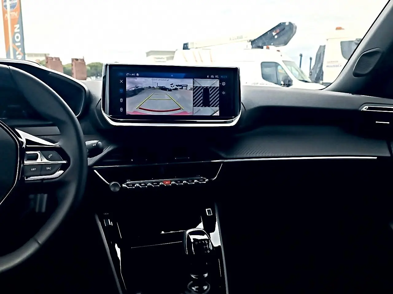 Vue intérieure du tableau de bord et écran tactile central du Peugeot 2008 rouge elixir 2025, avec caméra de recul affichée.