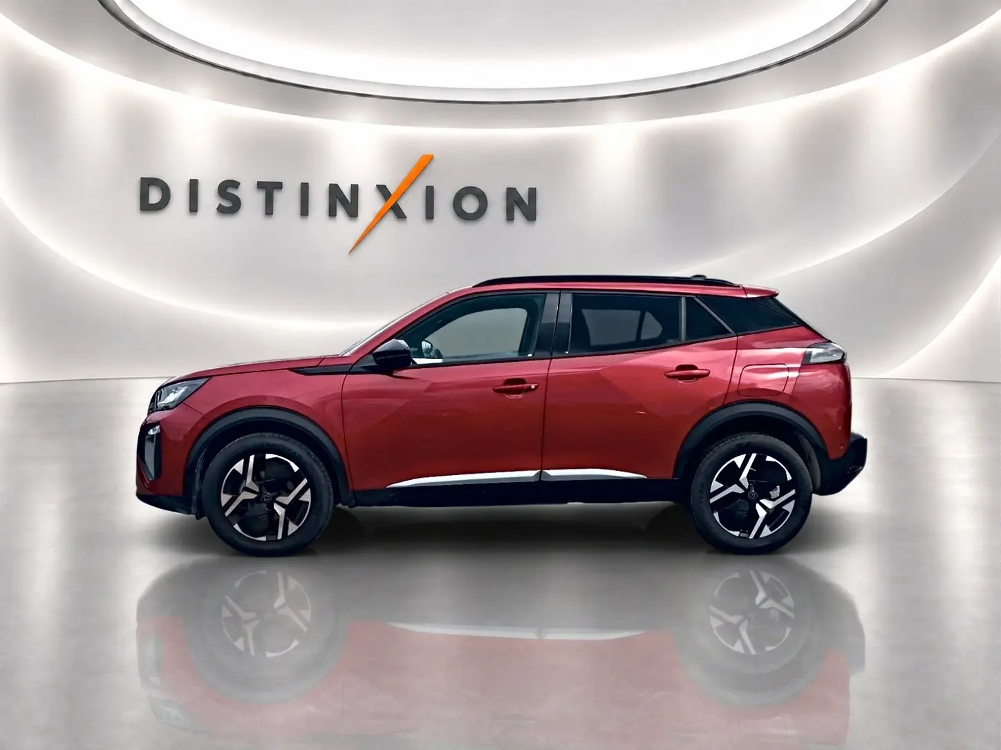 Profil droit du Peugeot 2008 rouge elixir 2025 avec jantes alu et toit noir dans un showroom lumineux.