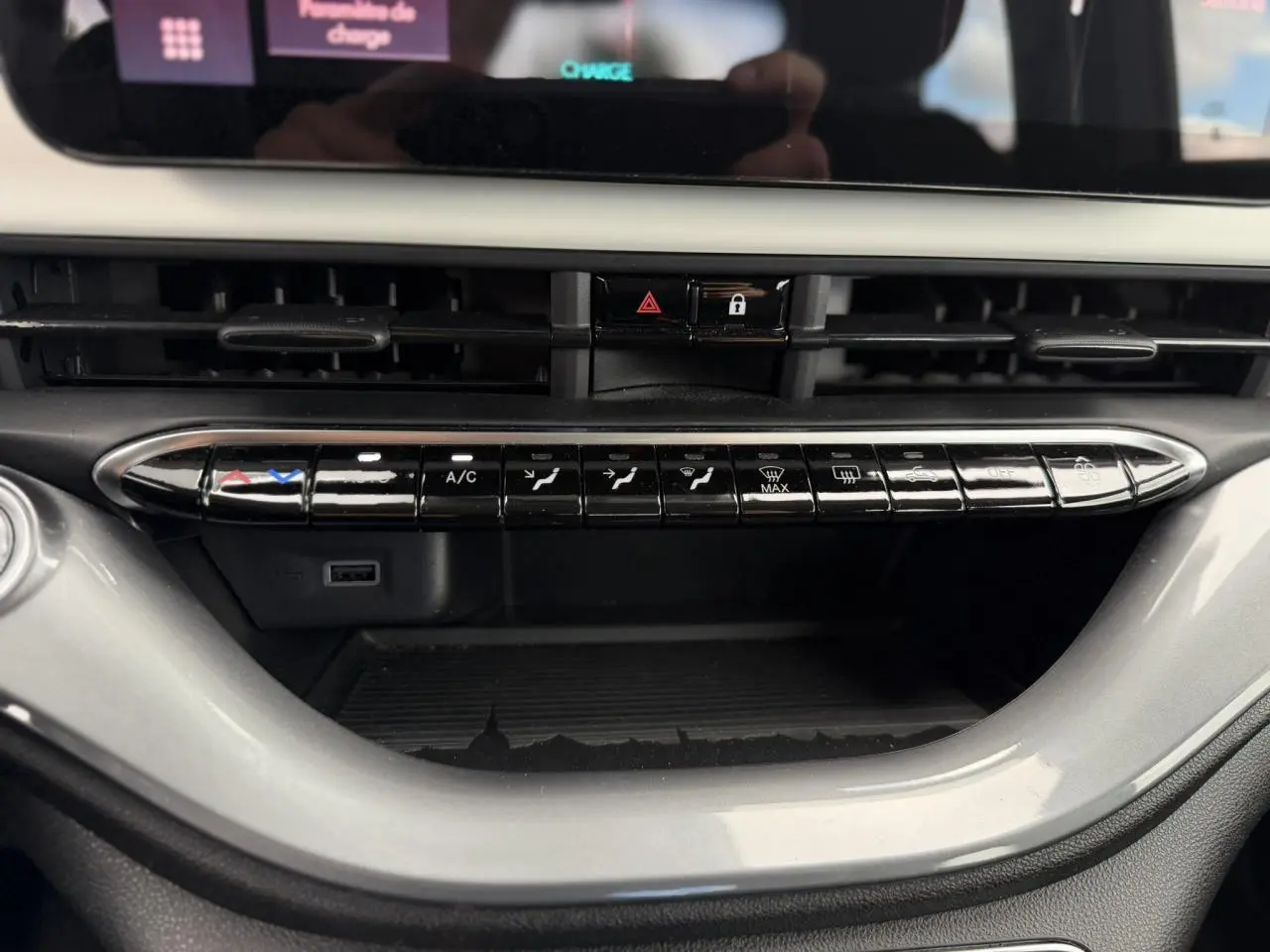 Vue rapprochée de la console centrale de la Fiat 500 électrique blanche, montrant les commandes de climatisation et un port USB.