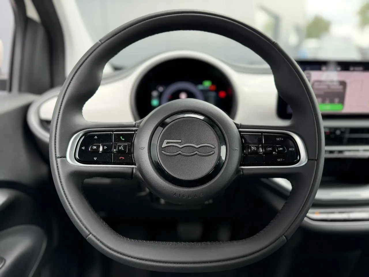 Volant noir Soft-Touch de Fiat 500 électrique 2024, vue frontale centrée avec tableau de bord blanc Artic en arrière-plan.