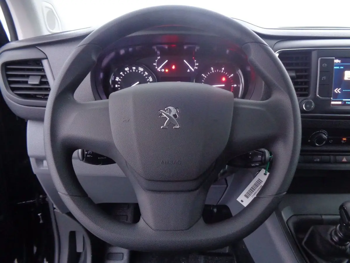 Vue rapprochée du volant noir du Peugeot Expert Fourgon 2022 avec tableau de bord et écran multimédia visibles.