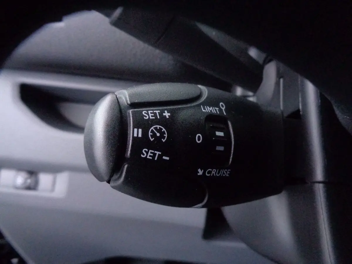 Gros plan sur la commande de régulateur de vitesse du Peugeot Expert Fourgon noir métal, version 2022, intérieur sombre.