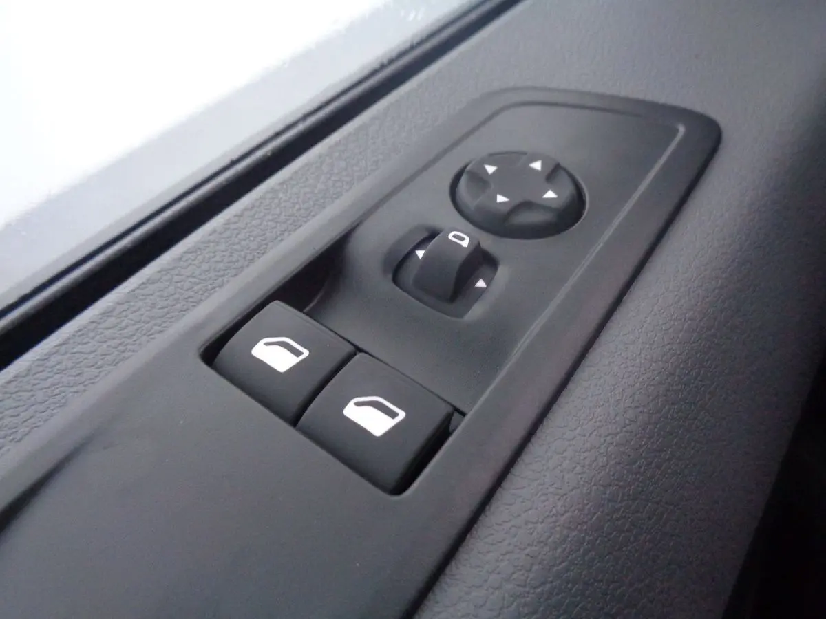 Gros plan sur les commandes de réglage des rétroviseurs et des vitres électriques côté conducteur du Peugeot Expert Fourgon noir métal 2022.