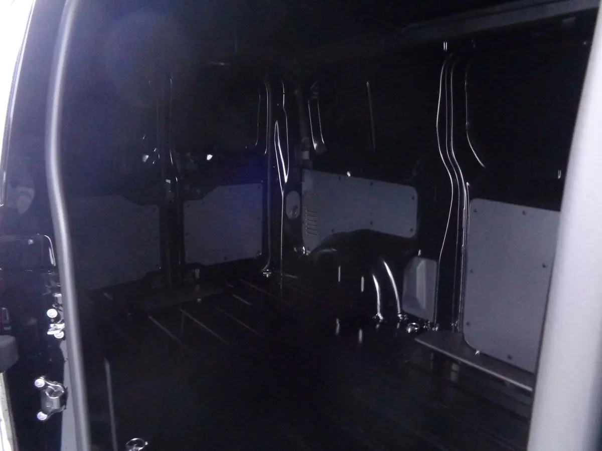 Intérieur du fourgon Peugeot Expert Standard noir métal 2022, vue depuis la porte latérale ouverte montrant l'espace de chargement vide.