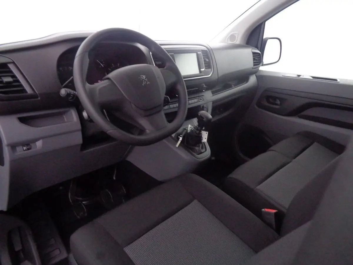 Vue intérieure côté conducteur du Peugeot Expert Fourgon 2022, tableau de bord noir avec volant et sièges gris foncé.