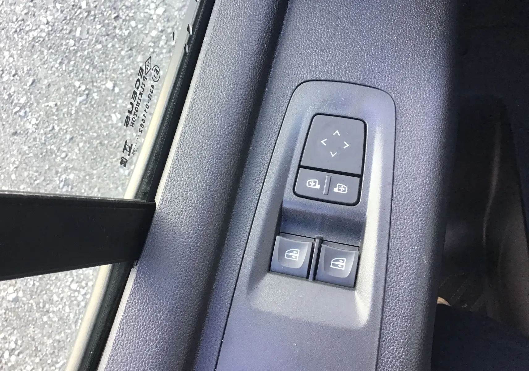Gros plan sur les commandes électriques des vitres et des rétroviseurs côté conducteur du Renault Master gris urbain 2025.