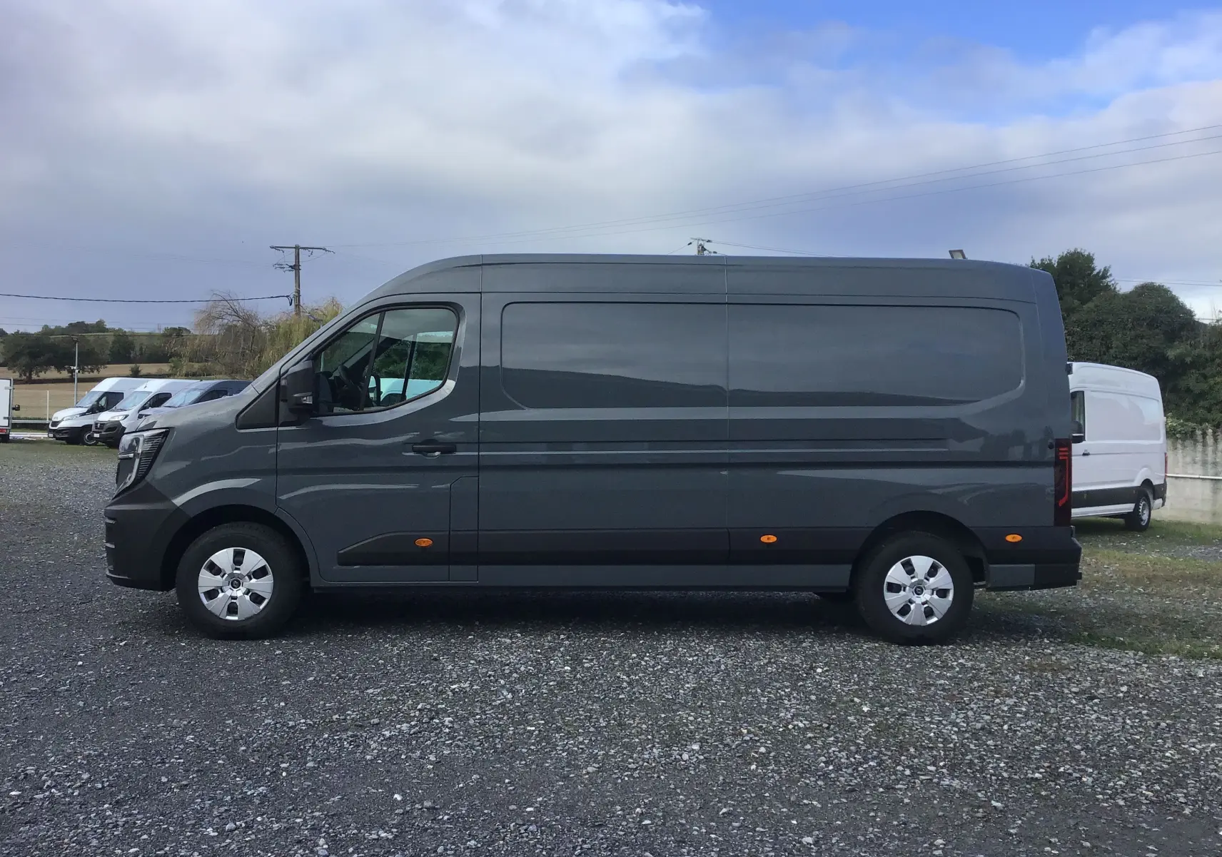 Vue de profil côté gauche du Renault Master L3H2 gris urbain 2025, avec feux latéraux orange et jantes argentées.