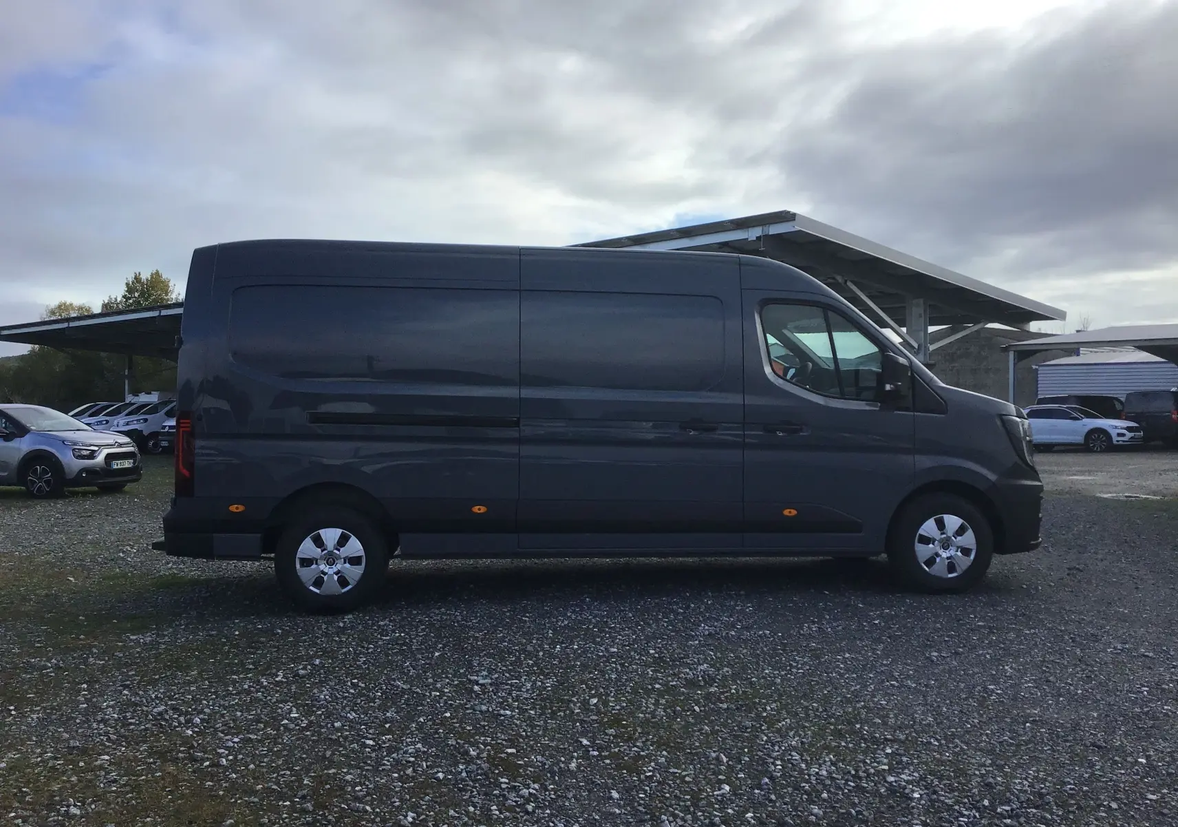 Renault Master L3H2 gris urbain vu de profil côté gauche, fourgon utilitaire avec jantes acier et feux latéraux orange.