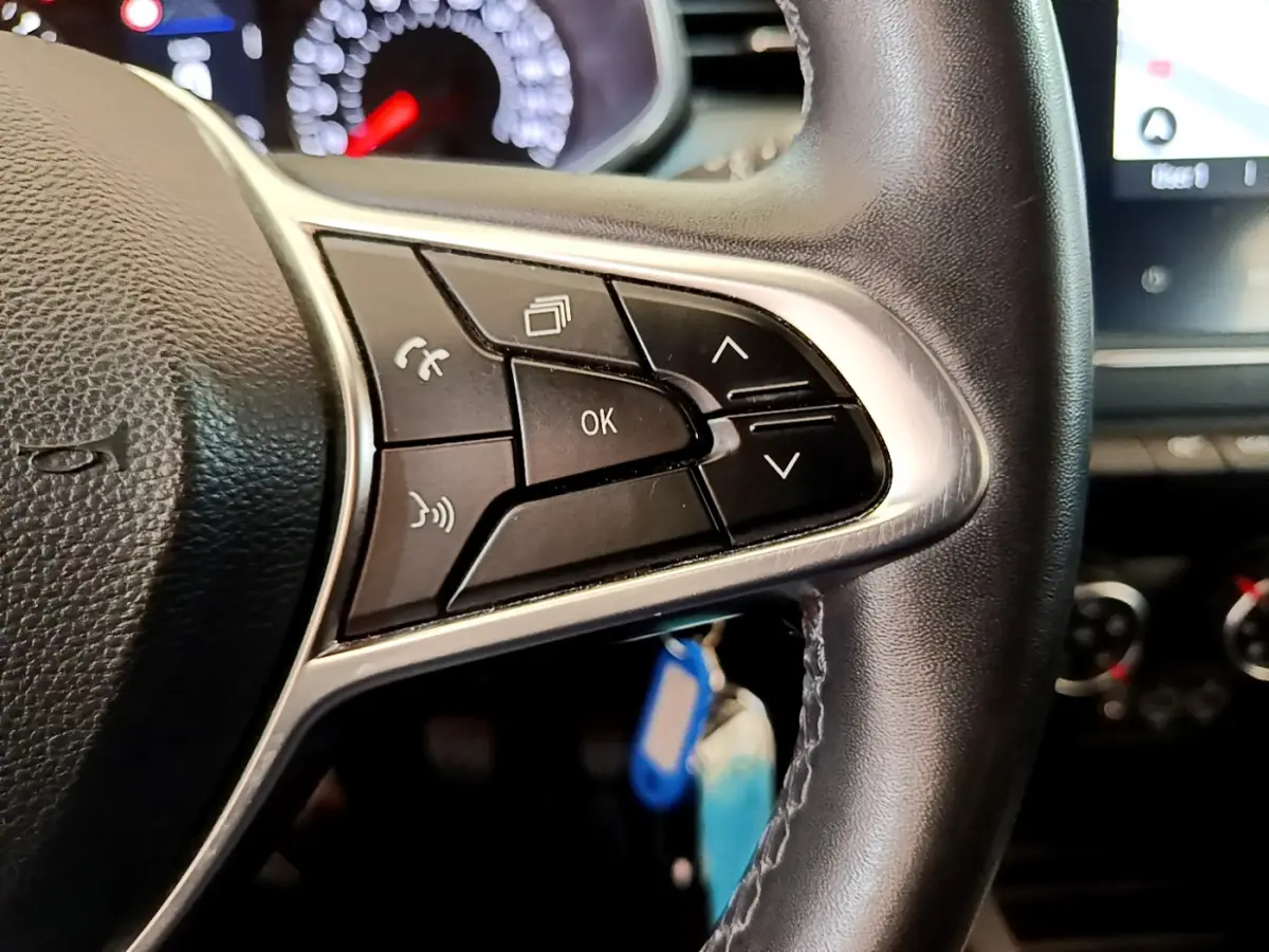 Gros plan sur les commandes multifonctions noires du volant en cuir synthétique de la Renault Clio Business Blue dCi 85, intérieur noir.