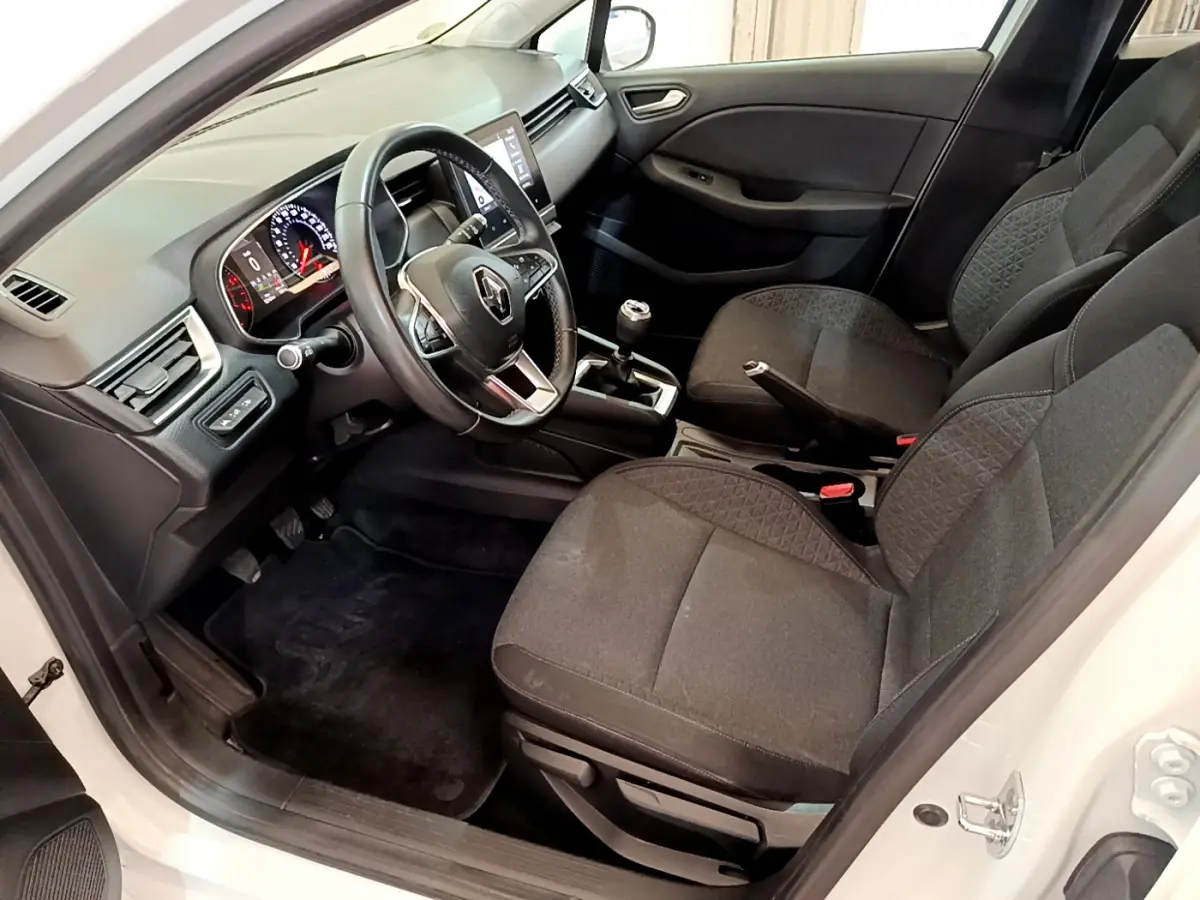 Vue intérieure côté conducteur de la Renault Clio Business Blue dCi 85 blanche, avec tableau de bord et volant multifonctions en cuir.