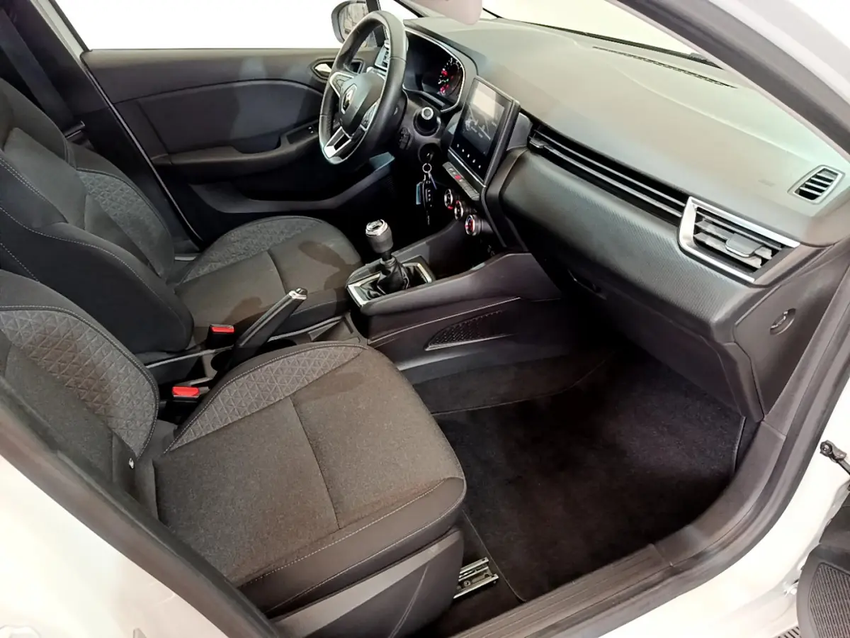Vue intérieure côté passager de la Renault Clio Business Blue dCi 85 blanche, montrant sièges noirs et tableau de bord moderne.